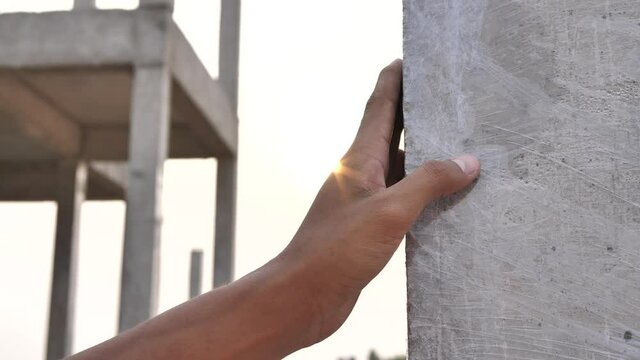 Workers' hands hold cement poles at construction sites, workers inspecting work, workers wearing helmets during sunset.