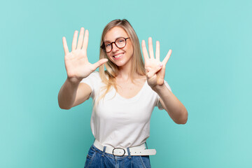 young blond pretty woman smiling and looking friendly, showing number nine or ninth with hand...