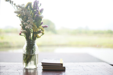 flower bouquet in glass vase and book near window