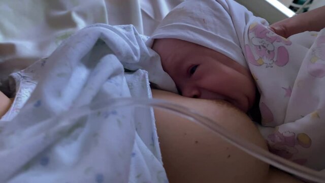 Breastfeeding within the first hour after birth, mom breastfeeding baby in the maternity hospital, skin-to-skin contact between mother and infant.