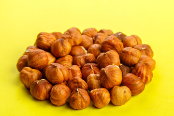 Peeled hazelnuts scattered on a yellow background.