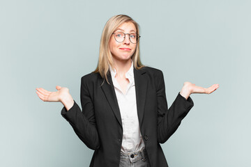 young pretty businesswoman feeling puzzled and confused, doubting, weighting or choosing different...
