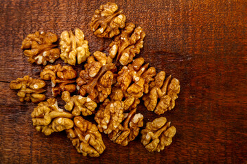 Walnuts sprinkled on a square board on a wooden table.