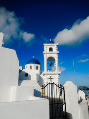 Whitewashed walls, tower and blue dome of one of the many churches on Santorini