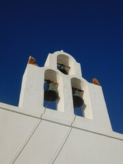 Whitewashed walls, tower and blue dome of one of the many churches on Santorini