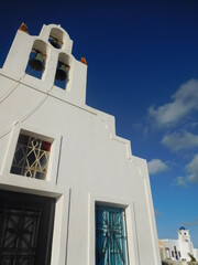 Whitewashed walls, tower and blue dome of one of the many churches on Santorini
