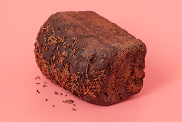 Rye bread sprinkled with cumin seeds on a pink background.