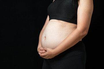 Asian woman standing post and placing hand on stomach on black background. Concept of weight loss for good health with excercise