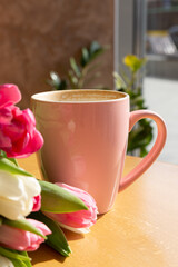 Cup of coffee and a bouquet of white and red tulips on the table. Happy mothers day.