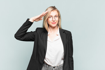 young pretty businesswoman greeting the camera with a military salute in an act of honor and...