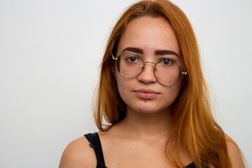 Obraz premium Red-haired girl on white background with glasses askew on face