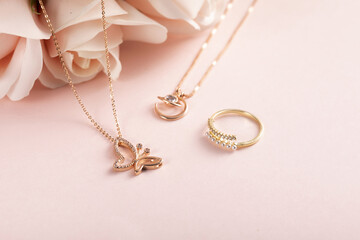 High angle shot of a beautiful ring and necklaces on a pink surface - obrazy, fototapety, plakaty