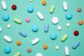 Different pills on color background, flat lay. Colorful pills and capsules on a green. Medicine concept.