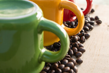 upside down red, green, yellow cups with coffee beans on wood