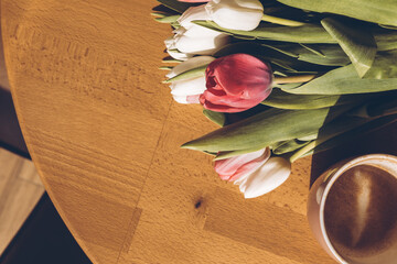 Cup of coffee and a bouquet of white and red tulips on the table. Happy mothers day.