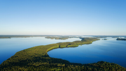 Aerial top view of beautiful blue water of beautiful lake. Birds eye view of scenic lake surrounded by pine forests.