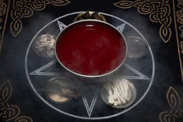 Goblet with blood on ritual table. Dark room with smoke. Black magic, occult concept. Witchcraft...