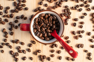 Coffee beans with a red cup and a spoon on wood