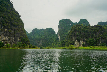 Green river flows between mountains in Vietnam