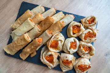 Homemade pancakes with red caviar, salmon, trout, red fish. Serving the dish on a graphite board.