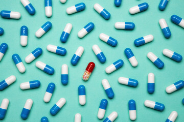 One red pill among blue capsules. Creative idea for uniqueness, innovation, different thinking. Healthy life, supplements, vitamins.