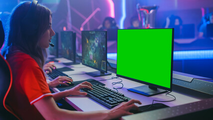 Pro Girl Plays Computer Game with Green Screen Display on a Championship. Diverse Esport Team of Pro Gamers Play in Mock-up RPG Strategy Video Game. Stylish Neon Cyber Games Arena. Side View © Gorodenkoff