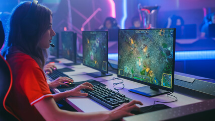 Pro Girl Plays Computer Game Plays RPG Strategy on a Championship. Diverse Esport Team of Pro Gamers Play in Mock-up Video Game. Stylish Neon Cyber Games Arena. Side View Shot © Gorodenkoff