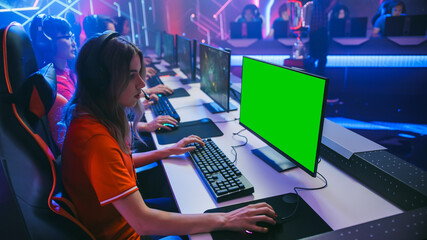 Pro Girl Plays Computer Game with Green Screen Display on a Championship. Diverse Esport Team of Pro Gamers Play in Mock-up RPG Strategy Video Game. Stylish Neon Cyber Games Arena. Side View © Gorodenkoff