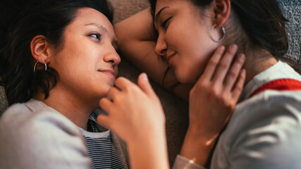 Happy Lesbian Couple at Home Lying, Cuddle, Touch Tenderly. Sunny Day Two Sensuous Girlfriends in Love Spend time Together, Share Authentic Beautiful Moments. Top Down Above Close-up Shot