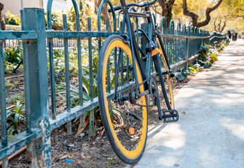 Fototapeta na wymiar Modern city bicycle strapped to a low fence near the footpath (507)