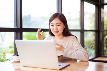 Obraz premium Asian happy woman working in coffee shop or co-working space.