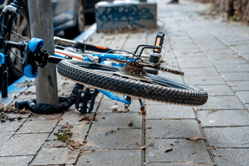 City sports bicycle strapped to a pole and lying on the sidewalk (508)
