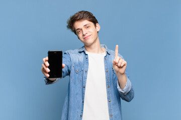 young boy smiling and looking friendly, showing number one or first with hand forward, counting...