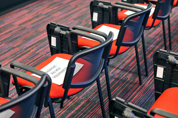 Red and black conference chairs in the auditorium with reservation for the speakers sign on them