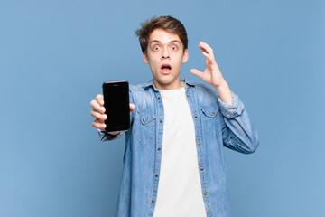 young boy screaming with hands up in the air, feeling furious, frustrated, stressed and upset. telephone concept