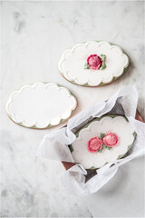 Delicate sugar cookies decorated with icing and fondant flowers on a marble table with copy space.