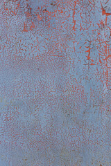 Texture of old peeling and cracked paint. Red is visible under blue