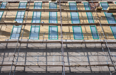 Scaffolding in front the building during the thermal insulation of walls with mineral wool and styrofoam.