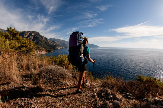 woman traveler with backpack on top of mountain enjoy on view of sea landscape.