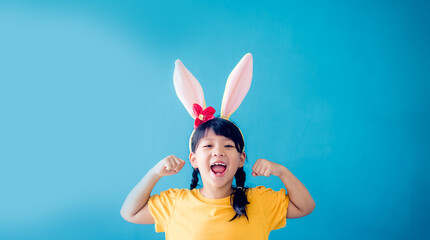 Cute little girl with bunny ears on color background.Strong superhero child.kid with muscles, milk,...