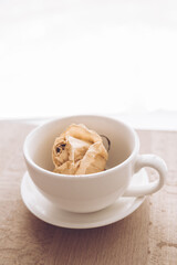 A small cup for tea with a saucer on the background of a beautiful view from the window. A cup for coffee with a flower bud inside.