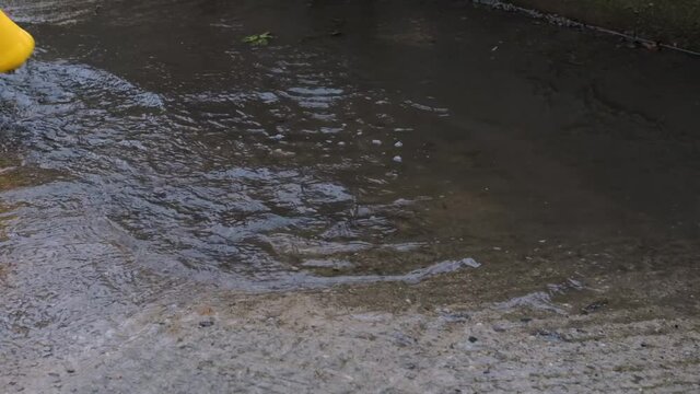 Run through puddle in yellow rubber boots and enjoy wet spring weather like little child. Video of legs without persons face. Enjoy and walk in rain.