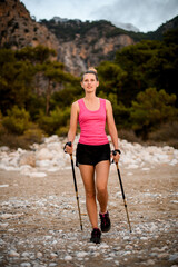 beautiful young woman walking along wild beach and mountains