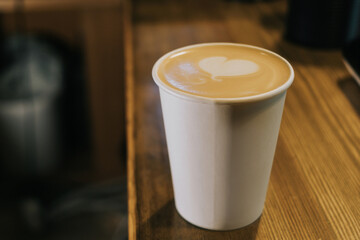 A paper coffee cup is on the counter in a coffee shop. Morning concept, coffee to go.