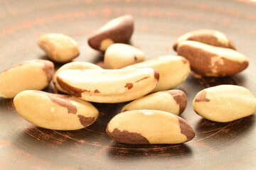 Several ripe organic Brazil nuts, close-up, on a clay plate.