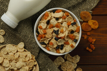 On the table is a plate of cornflakes, a spoon, and a bottle of milk