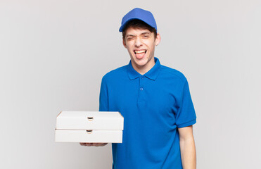 young pizza deliver boy with cheerful, carefree, rebellious attitude, joking and sticking tongue...