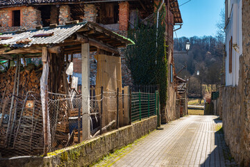 Torre Canavese, Italy. February 11th, 2021. A house with adjacent stacked wood storage in a narrow street of the town.