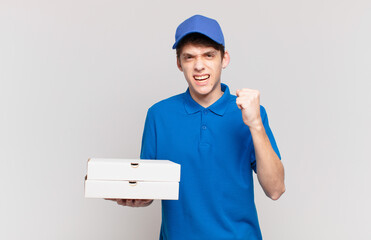 young pizza deliver boy shouting aggressively with an angry expression or with fists clenched...