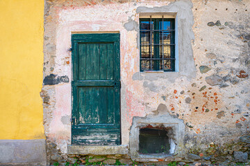 Fototapeta na wymiar Torre Canavese, Italy. February 11th, 2021. Historic building facade with wooden door and small window in the historic center of the town.